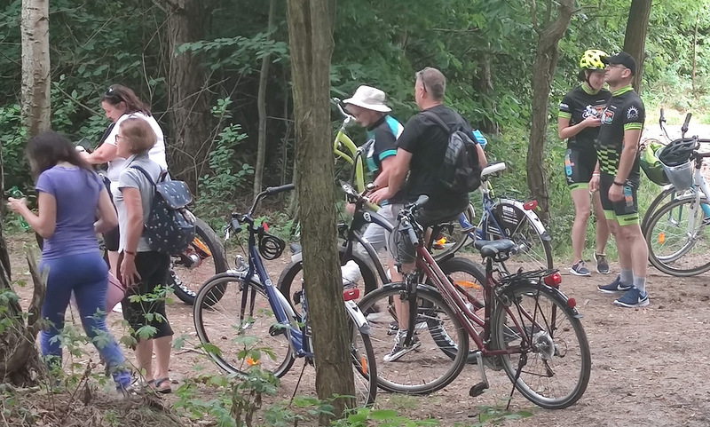 Uczestnicy rajdu rowerowego stojący w lesie między drzewami