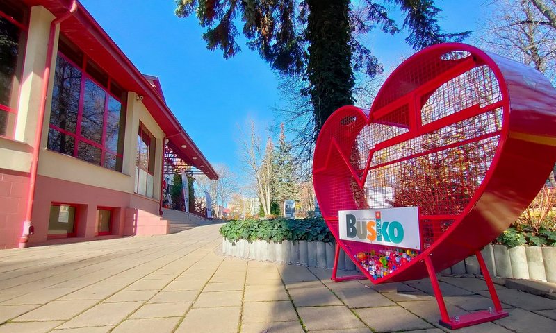 zdjęcie przedstawia pojemnik na nakrętki w kształcie serca stojący obok budynku BSCK w Busku-Zdroju