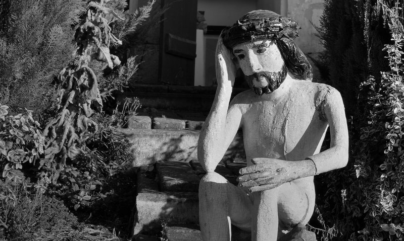 fragment czarno-białej fotografii Piotra Kalety przedstawiającej rzeźbę Jezusa Frasobliwego