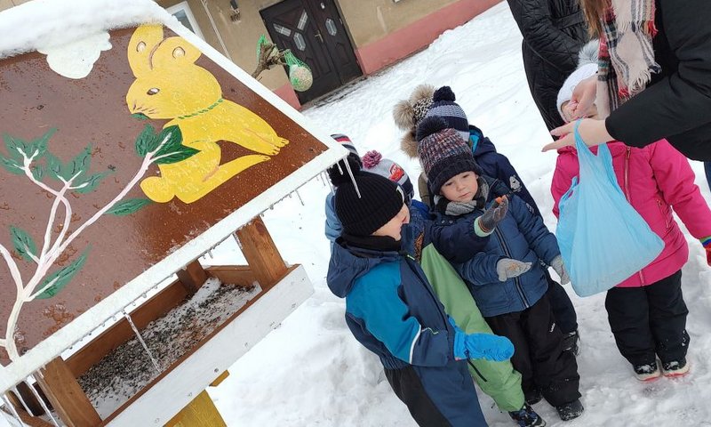 Przedszkolaki przy drewnianym karmniku dla ptaków