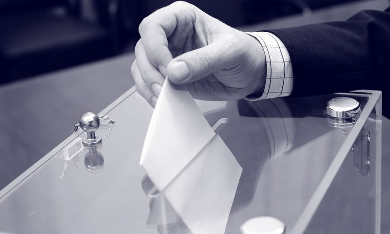 na zdjęciu  ręka osoby wrzucającej kartę do urny
