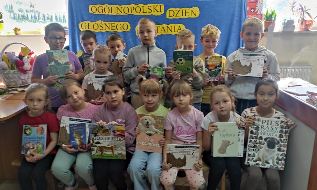 Dzieci pozują do zdjęcia trzymając w dłoniach książki