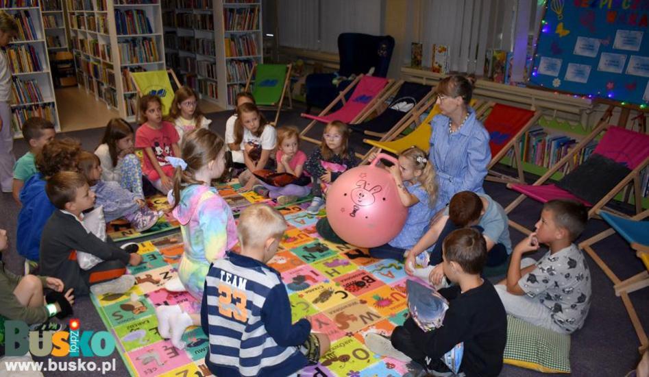 Dzieci siedzą na podłodze a mała dziewczynka trzyma piłkę Dzieci siedzą na podłodze a mała dziewczynka trzyma piłkę