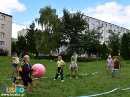 Dziewczynka biegnie trzymając w rękach dużą piłkę